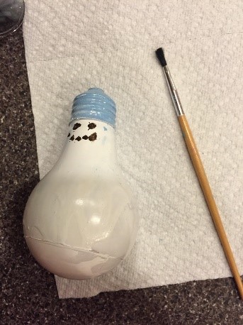 1.Spray paint the light bulbs.  Or purchase opaque, white bulbs. 2.	Paint on the face with black paint. 
