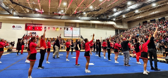Varsity cheerleaders and staff members perform at the Homecoming pep rally.