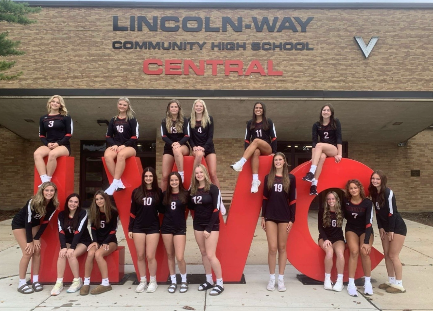 Girls Volleyball poses in front of the school.